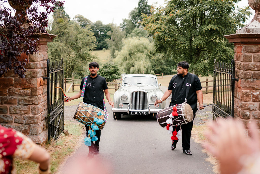 Baraat procession arriving down the tree-lined driveway